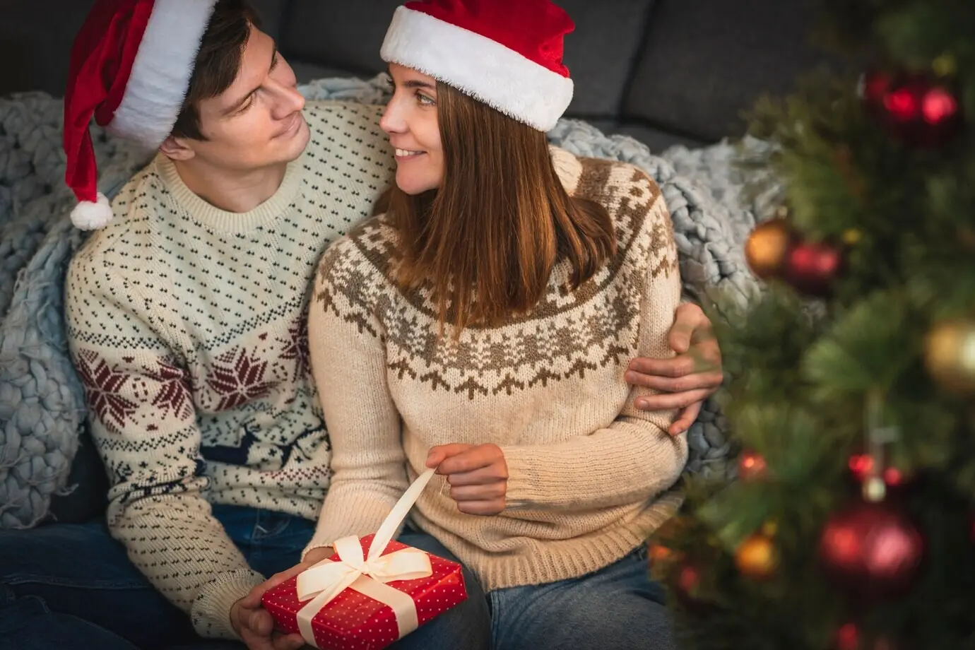 Niedliches Paar, das ein Weihnachtsgeschenk öffnet.